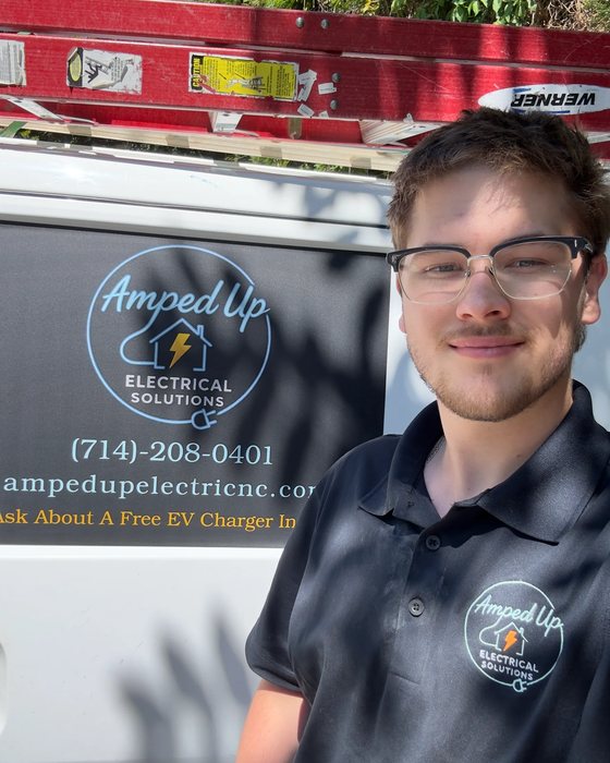 Amped Up electrician standing beside a branded company van on a Triad service call