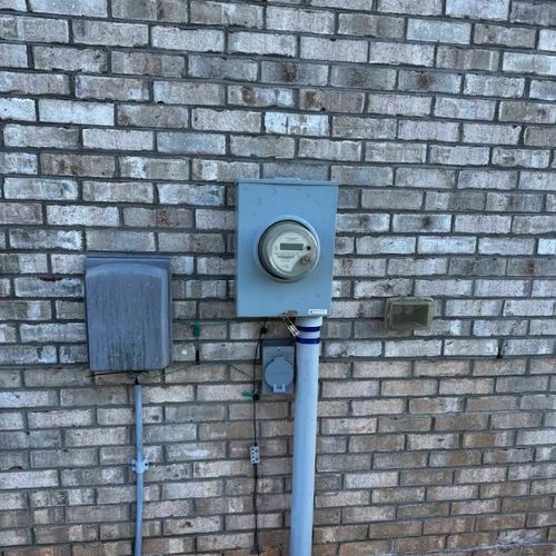 Electric meter and service conduit on the brick exterior of a home