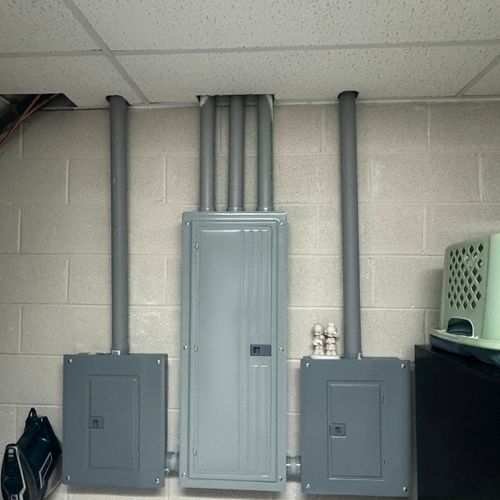Main panel and two subpanels installed with conduit on a garage wall