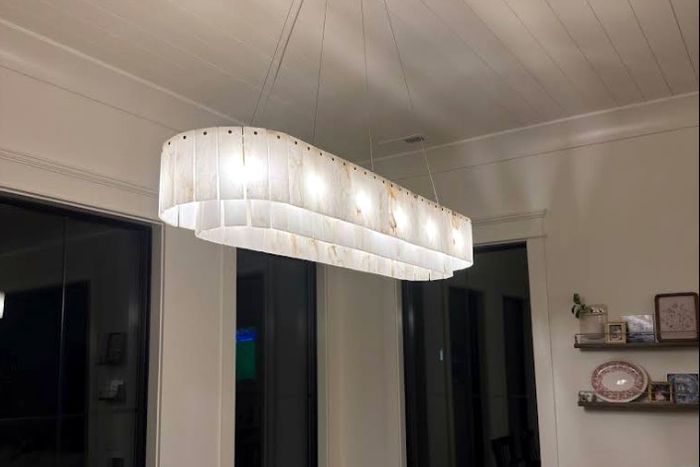 Linear chandelier lighting a dining room with a wall of windows