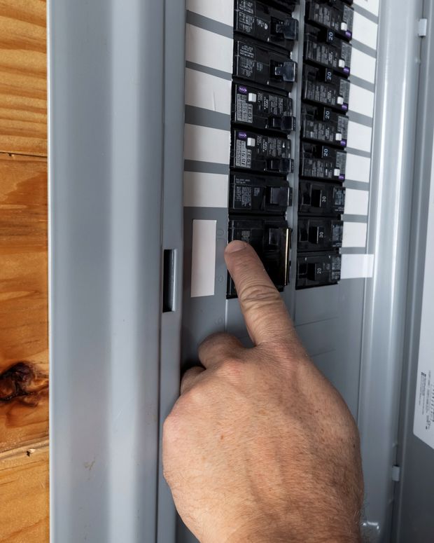 Electrician working a circuit breaker inside an open residential load center