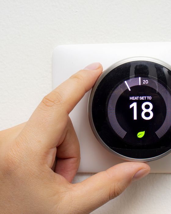 Hand turning a smart thermostat mounted on a wall