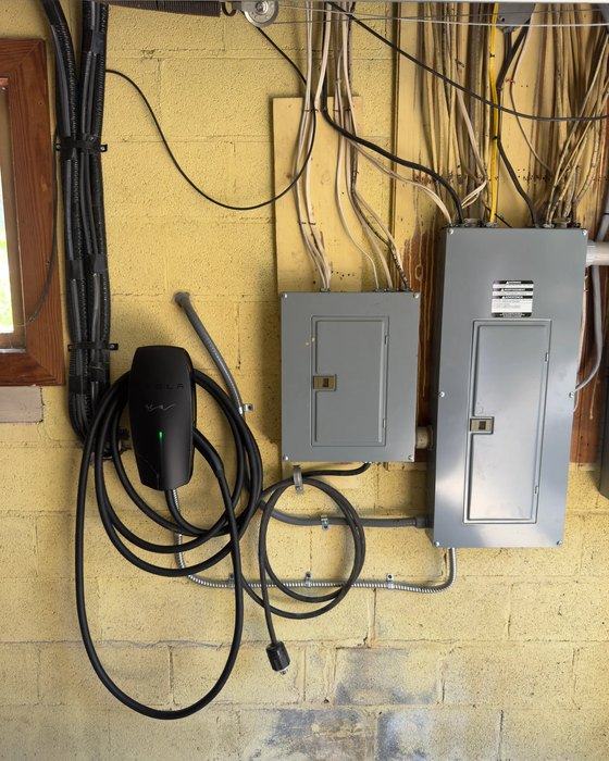 Subpanel and EV charging equipment mounted on a basement wall with conduit and branch wiring run to them
