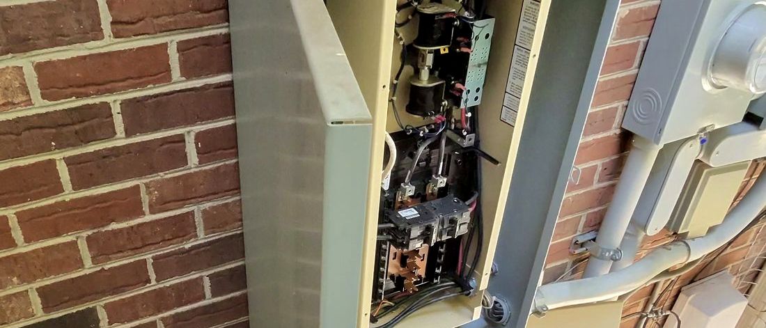 Close-up of transfer switch wiring and breakers inside the enclosure next to the electric meter