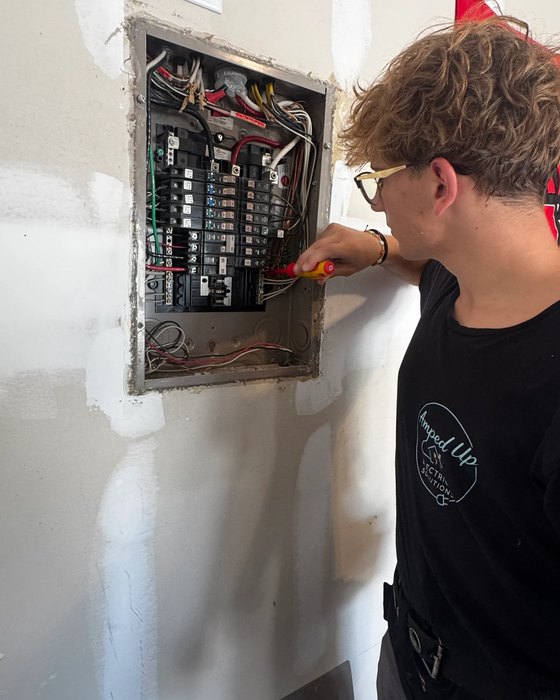 Amped Up electrician working at an open load center on a residential wiring job