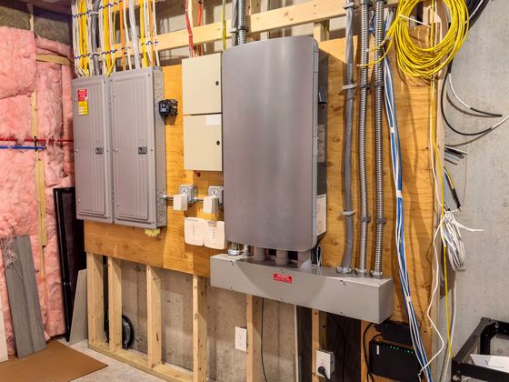 Panels and conduit along a basement wall on an Amped Up job