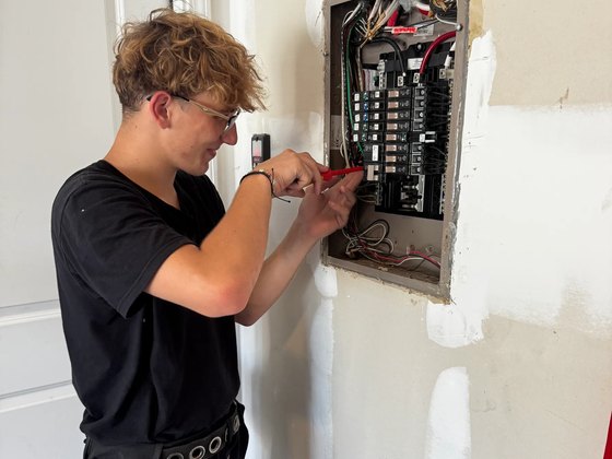 Amped Up electrician working at an open load center on a residential wiring job
